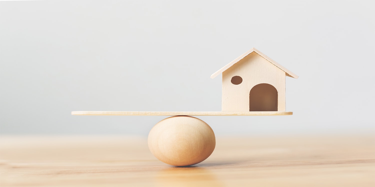 Wooden house balancing precariously, real estate investing risks concept